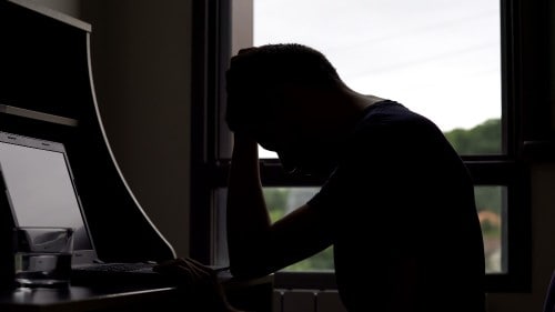 Head in hands at a computer station 